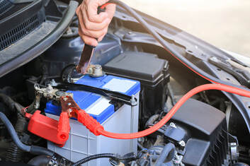 A picture of a person jump-starting a car battery. 